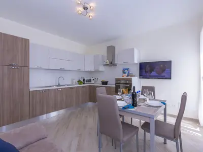 Blick auf Esstisch mit TV und ausgestatteter Küche