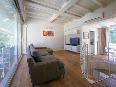 Das Wohnzimmer ist modern eingerichtet mit Klimaanlage und stilvollem Holzboden.