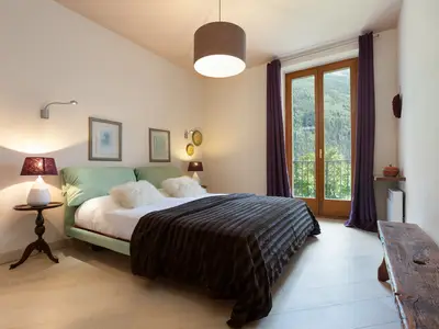 Erstes Schlafzimmer mit Doppelbett und Zugang zu einem Balkon