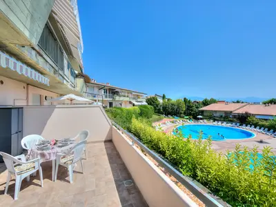 Balkon mit Tisch und Stühlen und Blick auf die beiden Pools