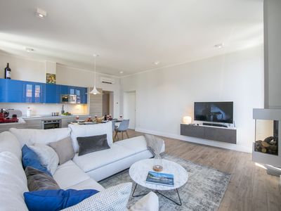 Wohnzimmer mit offener Küche, Fernseher und Kamin