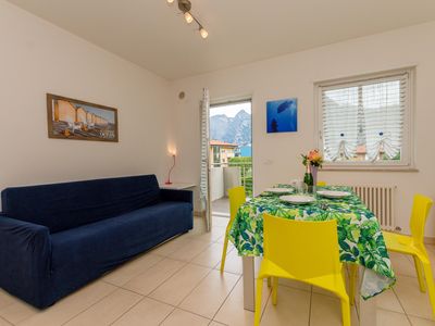 Das Wohnzimmer mit Schlafsofa, Esstisch und Ausgang zum Balkon