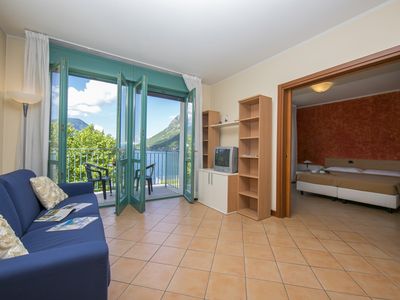 Wohnzimmer mit Zugang zum Balkon und Schlafzimmer mit Doppelbett