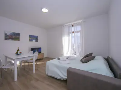 Das Wohnzimmer mit Esstisch, Schlafsofa und Eingang zum Balkon