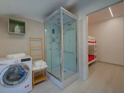 Badezimmer mit Hydromassage-Dusche, Waschbecken, Bidet, Toilette und Waschmaschine