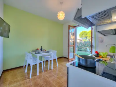 Wohnzimmer mit Esstisch, ausgestatteter Küche und Smart-TV