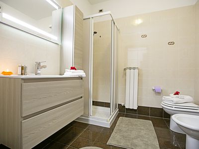 Badezimmer mit Waschmaschine, Bidet, Toilette und Waschbecken, Duschkabine