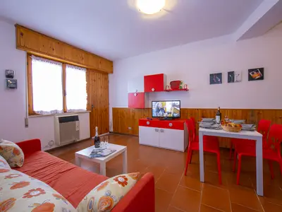 Das Wohnzimmer mit Esstisch, TV und Ausgang zur Terrasse