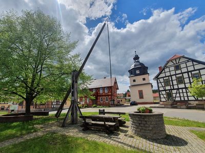 Dorfplatz mit Brunnen und Pension im Hintergrund