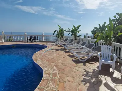 Pool mit Sonnenliegen und Blick auf Meer und Garten