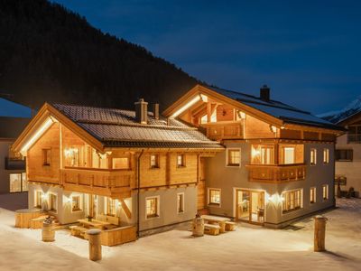 Engadin Chalet mit Aussenhot Pot by night und Hauptgebäude mit der Ferienwohnung