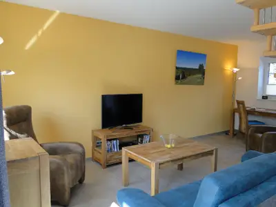 Wohnzimmer mit Smart-TV, DVD-Player und Ruhesesel