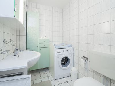 Badezimmer mit Waschmaschine und Waschbecken