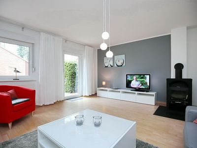 Wohnzimmer mit Sessel, TV und Kamin