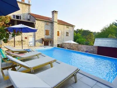 Das Äußere des Hauses mit Pool, Liegestühlen und Sonnenschirmen.