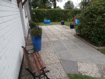 Terrasse. Hauseingang Nordseite mit Kinderbank, Sandmuschel und Rutsche-