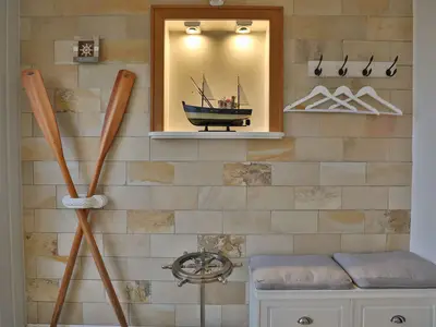 Nautic Lounge 45 – Maritimes Detail mit Deko-Ruder, Modellschiff & Garderobe, stilvoll eingerichtet.