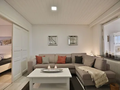 Nautic Lounge 45 – Gemütlicher Wohnbereich mit Ecksofa und Kerzen, modern-maritim eingerichtet in Scharbeutz-Haffkrug.
