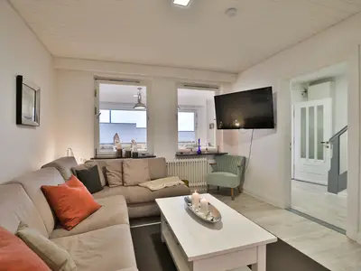Nautic Lounge 45 – Wohnbereich mit Ecksofa, TV und Blick ins Esszimmer, modern und maritim in Scharbeutz-Haffkrug.