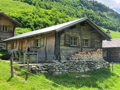 Alphütte Gental mit Sitzplatz und einem fixen Gartentisch mit 6 Stühlen.