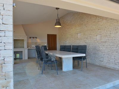 Außenküche mit Holzgrill, Doppelherdplatte und Waschbecken sowie gemütlichem Sitzbereich