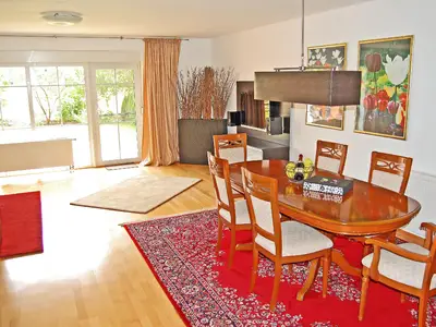 Essbereich und großer Wohnbereich mit großem Smart-TV und Zugang zum Garten und Spielplatz.
