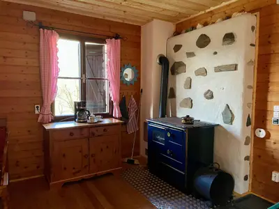 Kochnische mit Holzofen, elektrischen Kochplatten, Geschirr und Kaffeemaschine