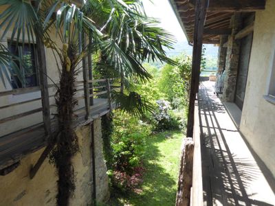 Gedeckter Balkon, der zu den Zimmern und zur oberen Terrasse mit Weitsicht führt, Garten mit Palmen