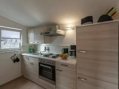 Komplett ausgestattete Küche mit Kühlschrank, Backofen, Kaffeemaschine, Wasserkocher, Toaster und Geschirr.