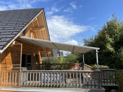 Holzterasse auf Südseite mit Markise und Zugang zum Garten