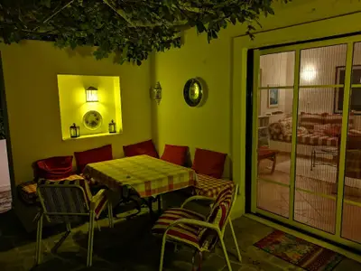 Terrasse. Sitzplatz  weinlaub-überdacht. Blick ins Wohnzimmer mit seperater Glas-und Mückengitter-Schiebetür.