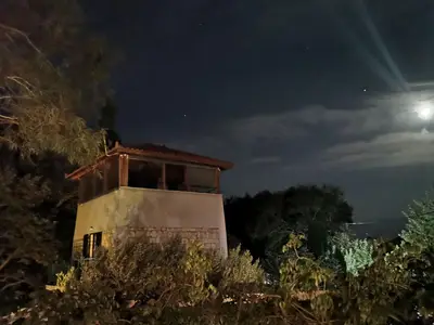 Außenansicht des Gebäudes. Die "Turmspitze" im Mondlicht. Rechts im Hintergrund das Meer.