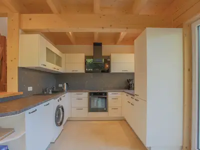 Einfamilienhaus Am Hafen 21 in Zieslow — moderne U-Küche mit Einbaugeräten, Steinrückwand und offen zum Wohnzimmer