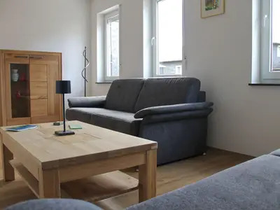 Im heimeligen Wohnzimmer stehen 2 Schlafsofas. Für Unterhaltung sorgt der große Fernseher mit Magenta TV