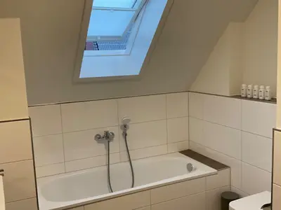 Badezimmer mit Badewanne, Dusche und Fenster.