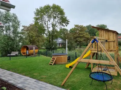 Außenbereich mit Spielplatz, Sauna und Garten.