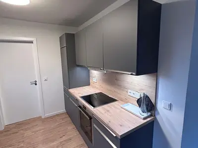 Moderne Küche mit Holzarbeitsplatte und Kühlschrank.