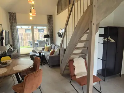 Moderner Wohnraum mit Treppe und großen Fenstern.