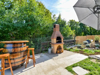 Gemauerter Grill mit Fasstisch und Holzstühlen