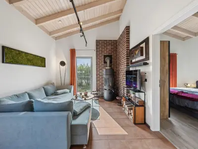 Die Sitzecke mit TV und dänischem Holzofen - angeschnitten das Doppelbettschlafzimmer