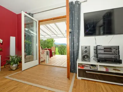 Wohnzimmer mit Flachbild-TV 55 Zoll und Blick auf Wintergarten und Garten