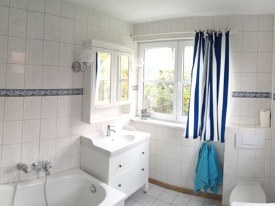 Badezimmer mit Spiegel, Waschbecken, WC und Badewanne