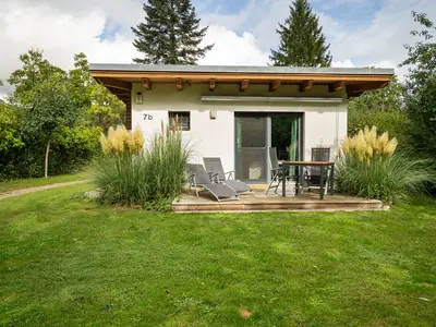 Ferienhaus Kleine Sommerliebe Waren (Müritz) - Holzterrasse mit Gartenmöbeln und Liegestühlen umgeben von Ziergräsern
