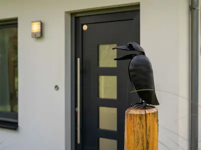 Ferienhaus Kleine Sommerliebe Waren (Müritz) - Dekoratives Eingangselement mit Vogel-Skulptur und schwarzer Haustür
