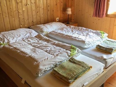 Schlafzimmer mit 2 Betten, Nachttischen, 2 Korbstühlen, Kommode und Schrank.