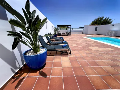 Große, sonnige Terrasse: Außenbereich mit Liegestühlen, Schwimmbad und schattigem Bereich.