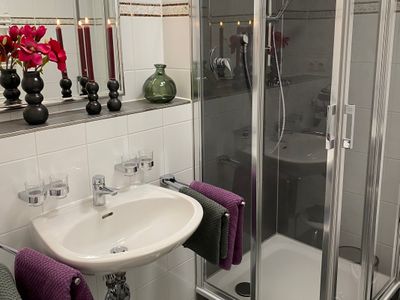 Badezimmer mit Dusche, Waschbecken und Spiegel