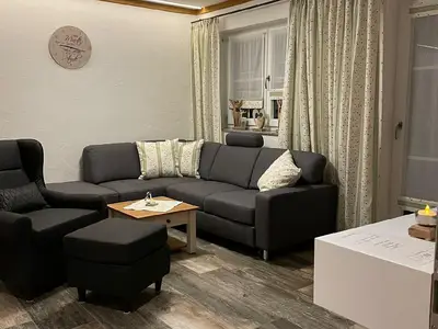 Wohnbereich. Ausziehsofa mit Ohrensessel und Fußhocker