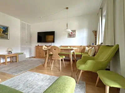 Wohnraum mit Flat-TV, Couch, Essecke und Balkon