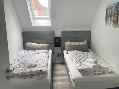 Schlafzimmer mit zwei von einer Nachttischlampe getrennten Einzelbetten